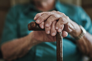 close up of an elderly woman's hands resting on a walking cane