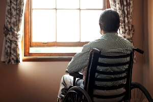 picture of elderly man sitting in a wheelchair and looking out window