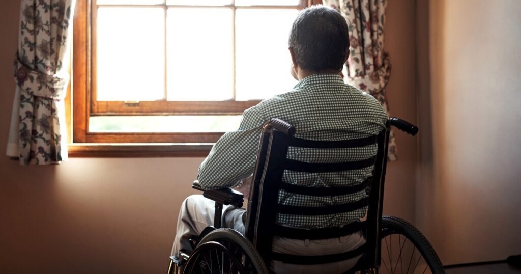 picture of elderly man sitting in a wheelchair and looking out window