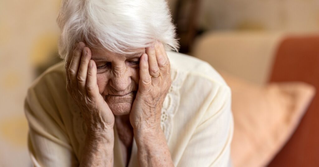 elderly woman holding her face, upset