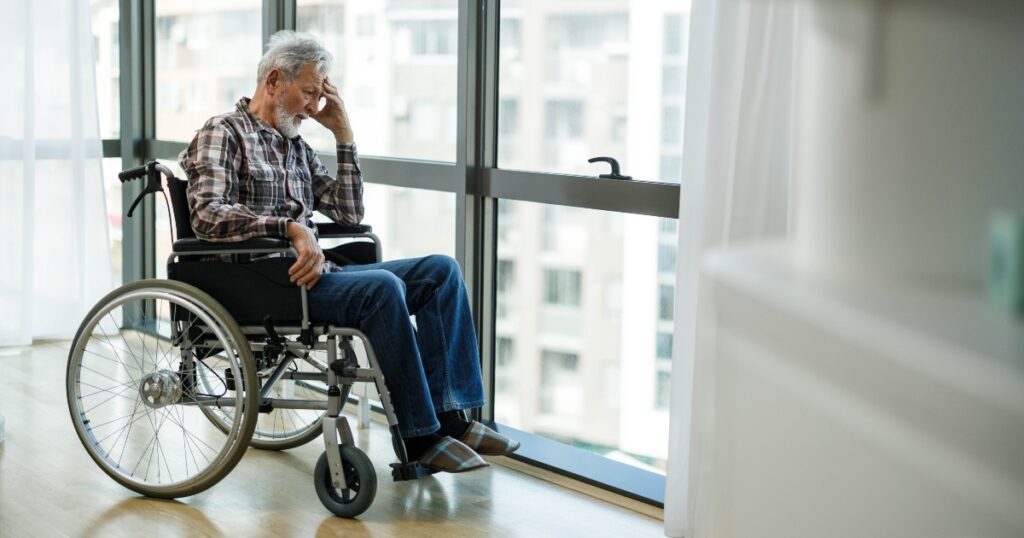 elderly man sitting alone in wheelchair and looking out window