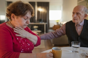 A male resident looks concerned about a female resident choking on her food