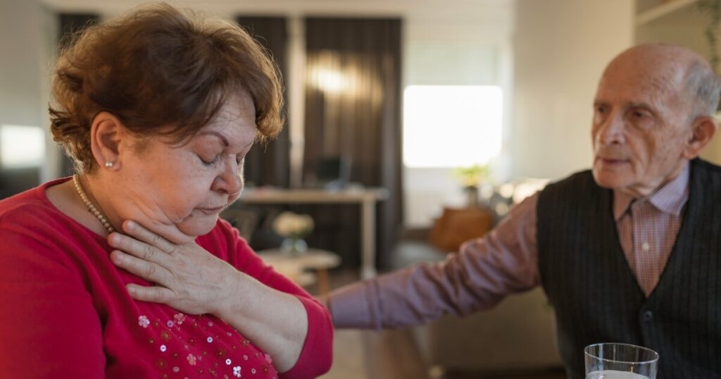 A male resident looks concerned about a female resident choking on her food