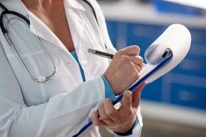 Medical professional taking notes on a paper notepad during a site inspection